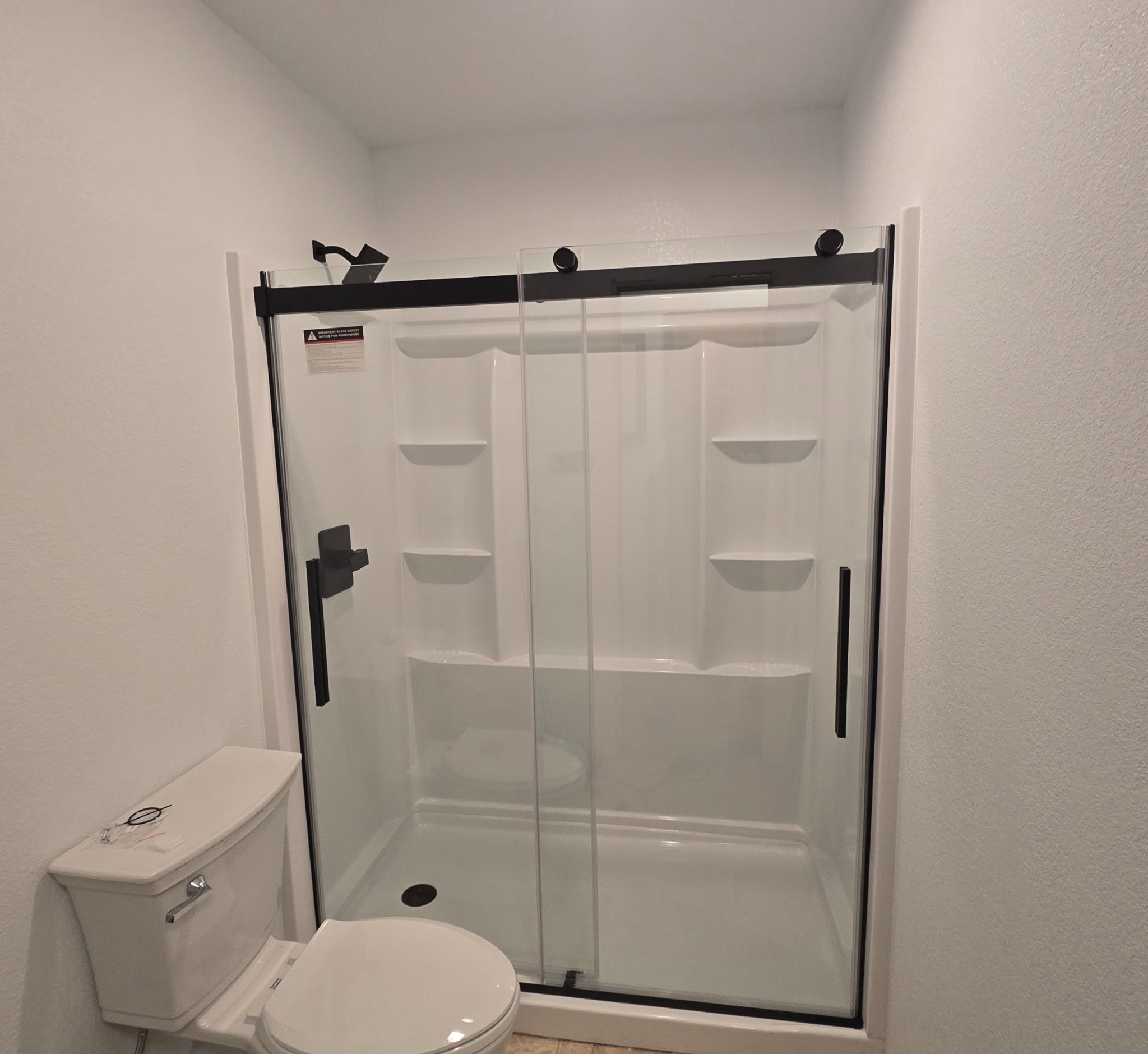 Bathroom shower installation with sliding glass doors and black hardware