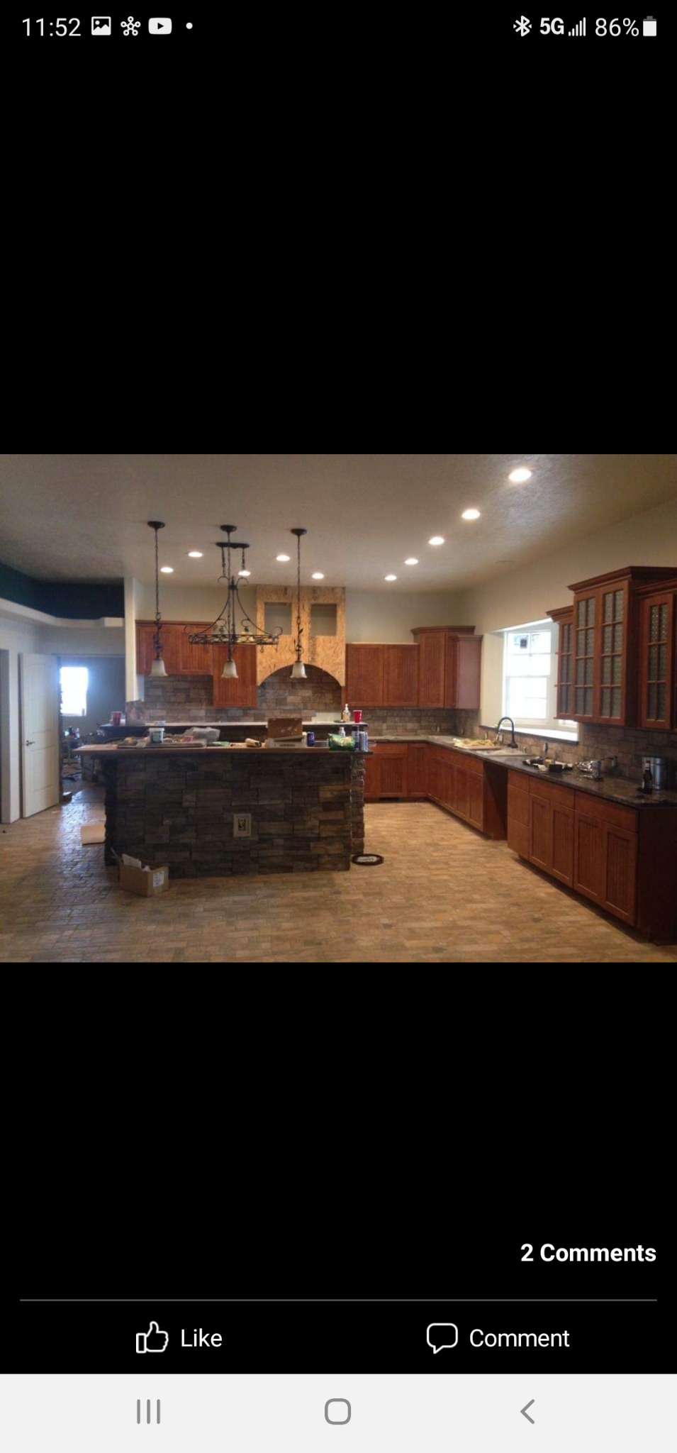 Kitchen project with wood cabinetry, stone-faced island and range hood